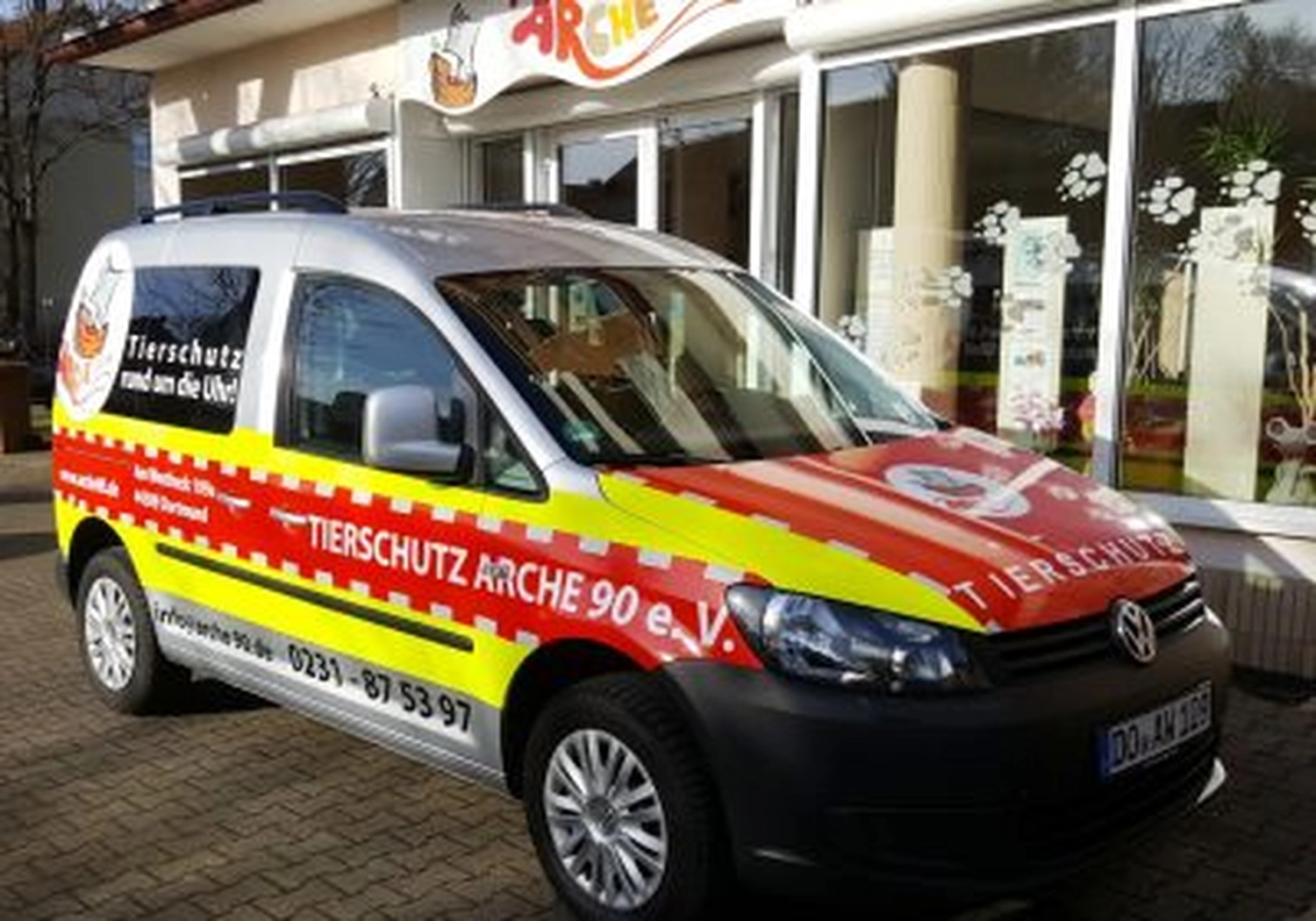 Tierschutzorganisation Arche 90 e.V. - Ein rot-weißer VW-Rettungswagen mit der Aufschrift „TIERSCHUTZ ARCHE 90 e.V.“ an der Seite parkt auf der Straße.