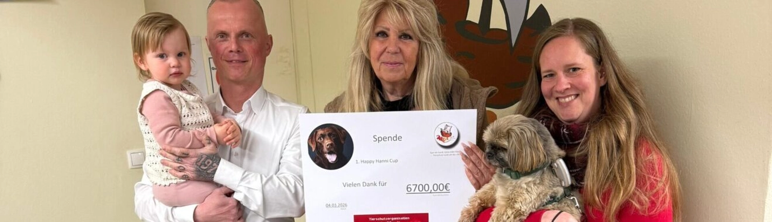 Tierschutzorganisation Arche 90 e.V. -  Drei Personen, ein Kind und ein kleiner Hund lächeln, während sie einen großen Spendenscheck über 6.700 Euro in den Händen halten.