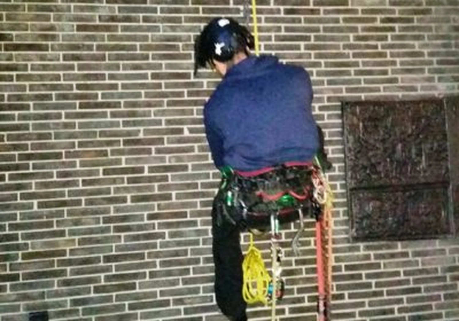 Tierschutzorganisation Arche 90 e.V. - Eine Person mit Helm und Sicherheitsgurt seilt sich mit bunten Kletterseilen eine hohe Backsteinmauer ab.