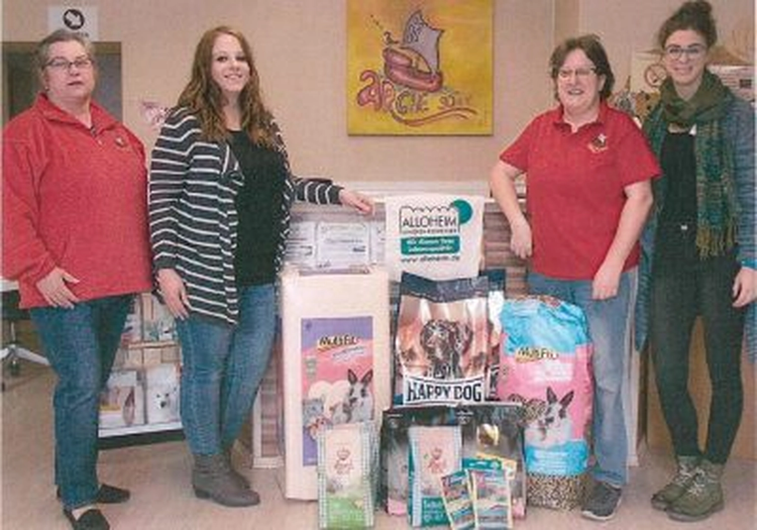 Tierschutzorganisation Arche 90 e.V. - Ein Foto von vier Frauen, die drinnen neben großen Säcken mit Tierfutter und Zubehör auf einem Tisch posieren.